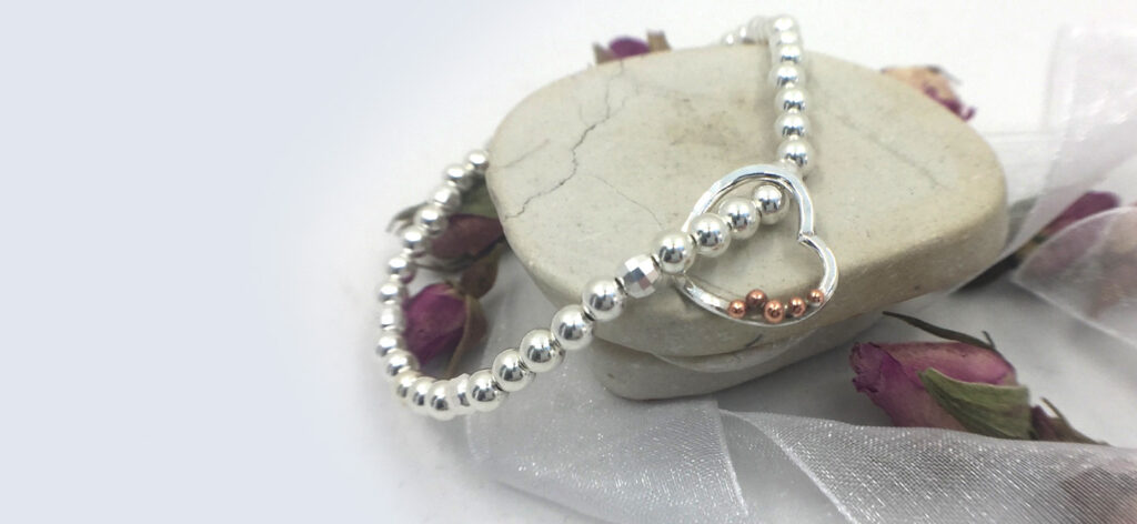 silver bead stretch bracelet with bespoke heart charm with copper pebble details