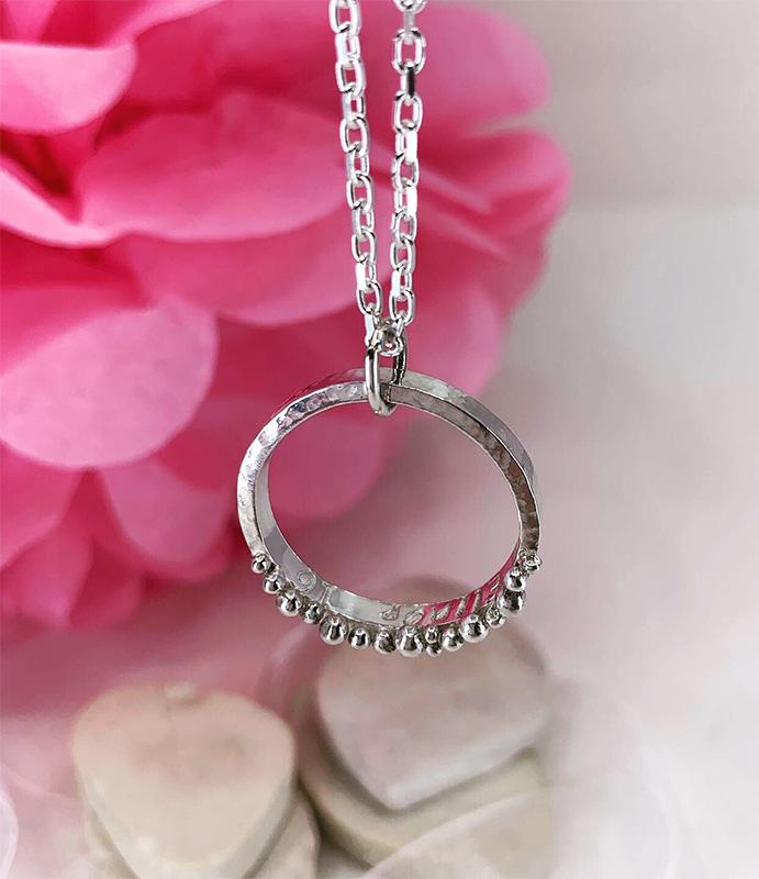 Personalised recycled silver circle necklace with custom pebbles and name.