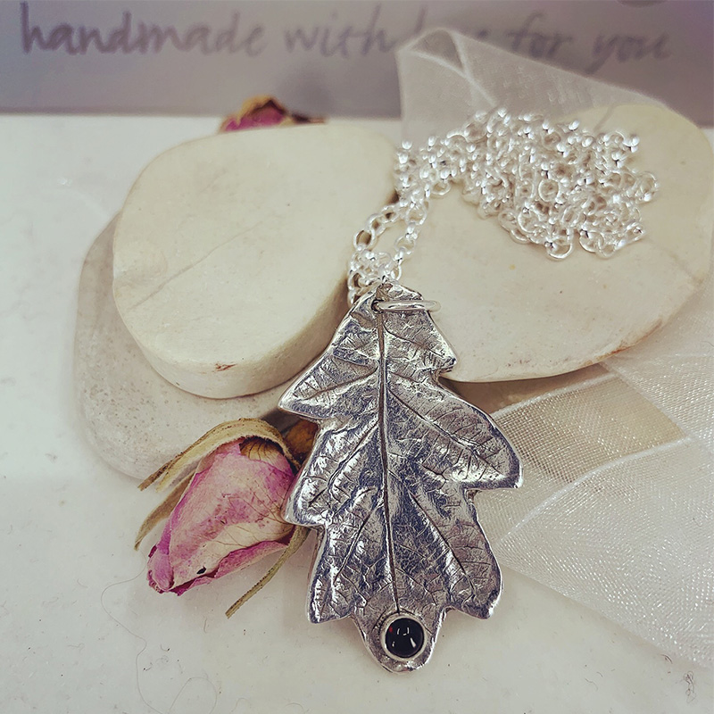 a fine silver oak leaf pendant with a garnet