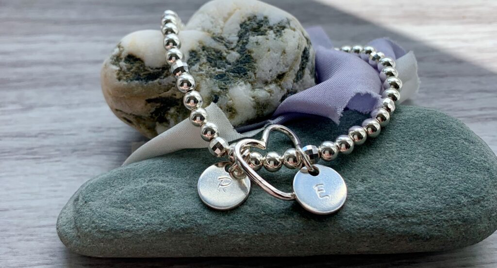 silver bead stretch bracelet personalised with open heart charm and two discs with initials